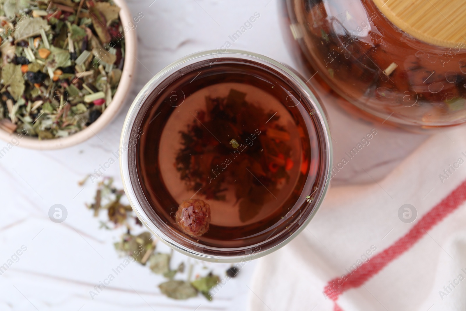 Photo of Delicious herbal tea and dry leaves on white table, flat lay