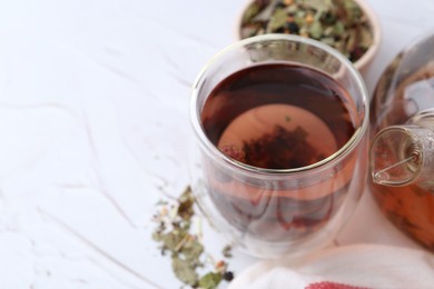 Photo of Delicious herbal tea and dry leaves on white table, closeup. Space for text