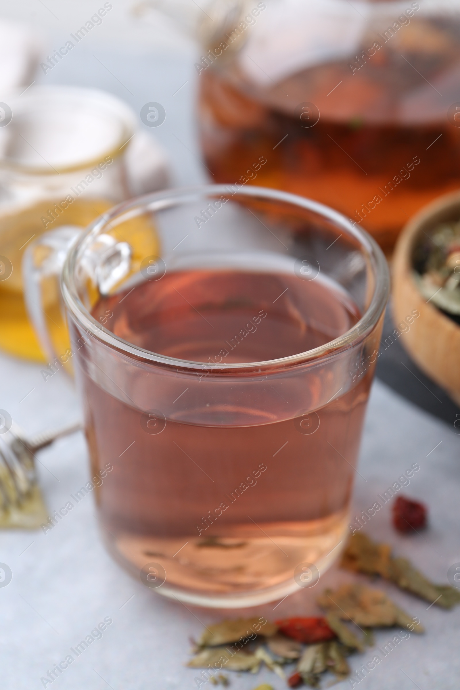 Photo of Delicious herbal tea and dry leaves on grey table, closeup