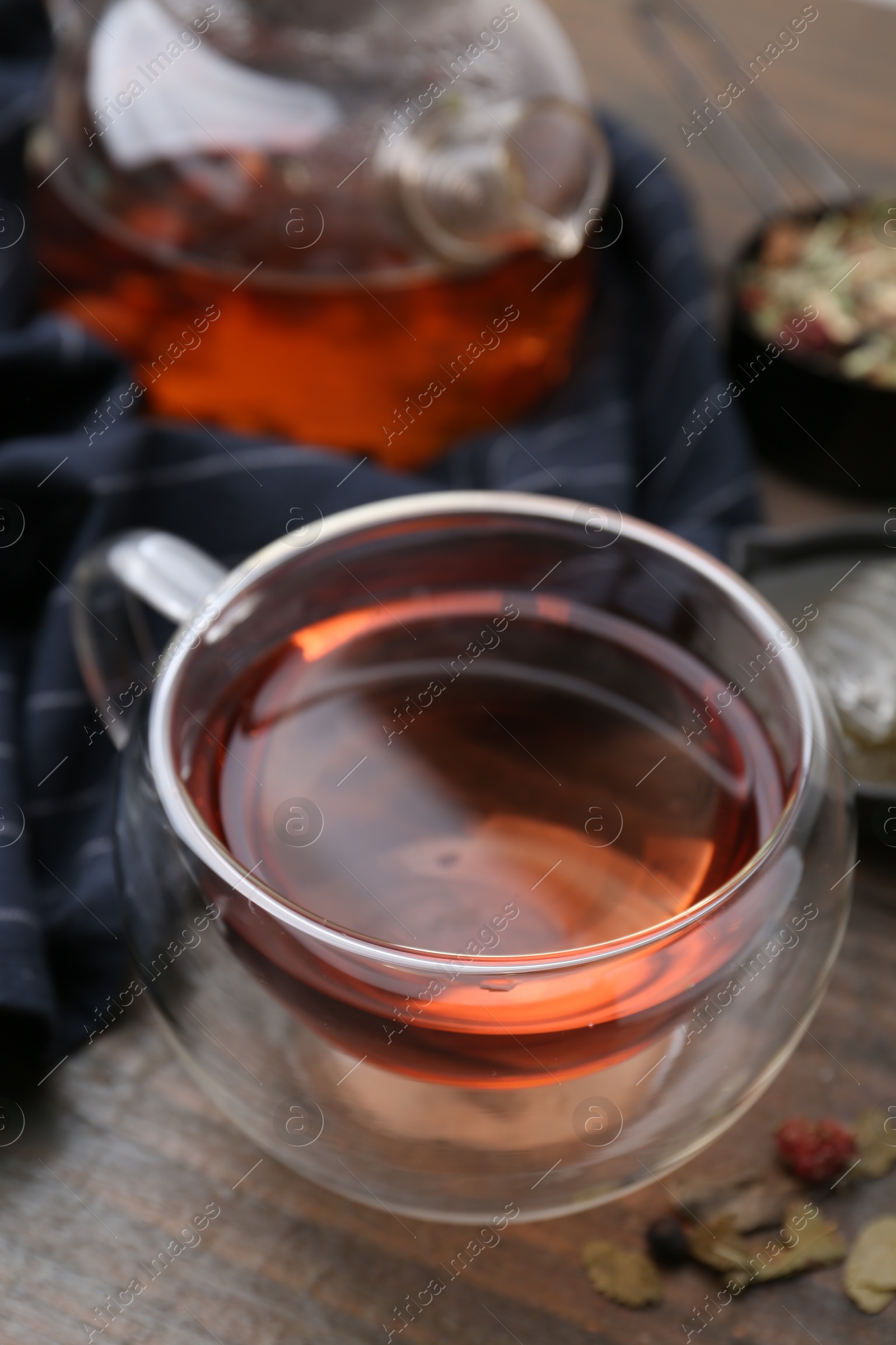 Photo of Delicious herbal tea and dry leaves on wooden table, closeup