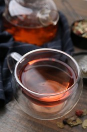 Photo of Delicious herbal tea and dry leaves on wooden table, closeup