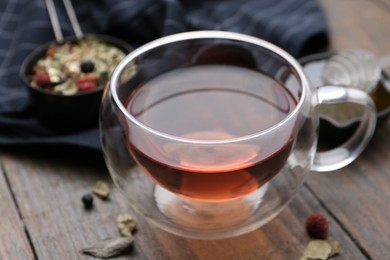 Photo of Delicious herbal tea and dry leaves on wooden table, closeup