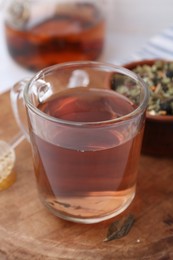 Photo of Delicious herbal tea, honey and dry leaves on white table, closeup