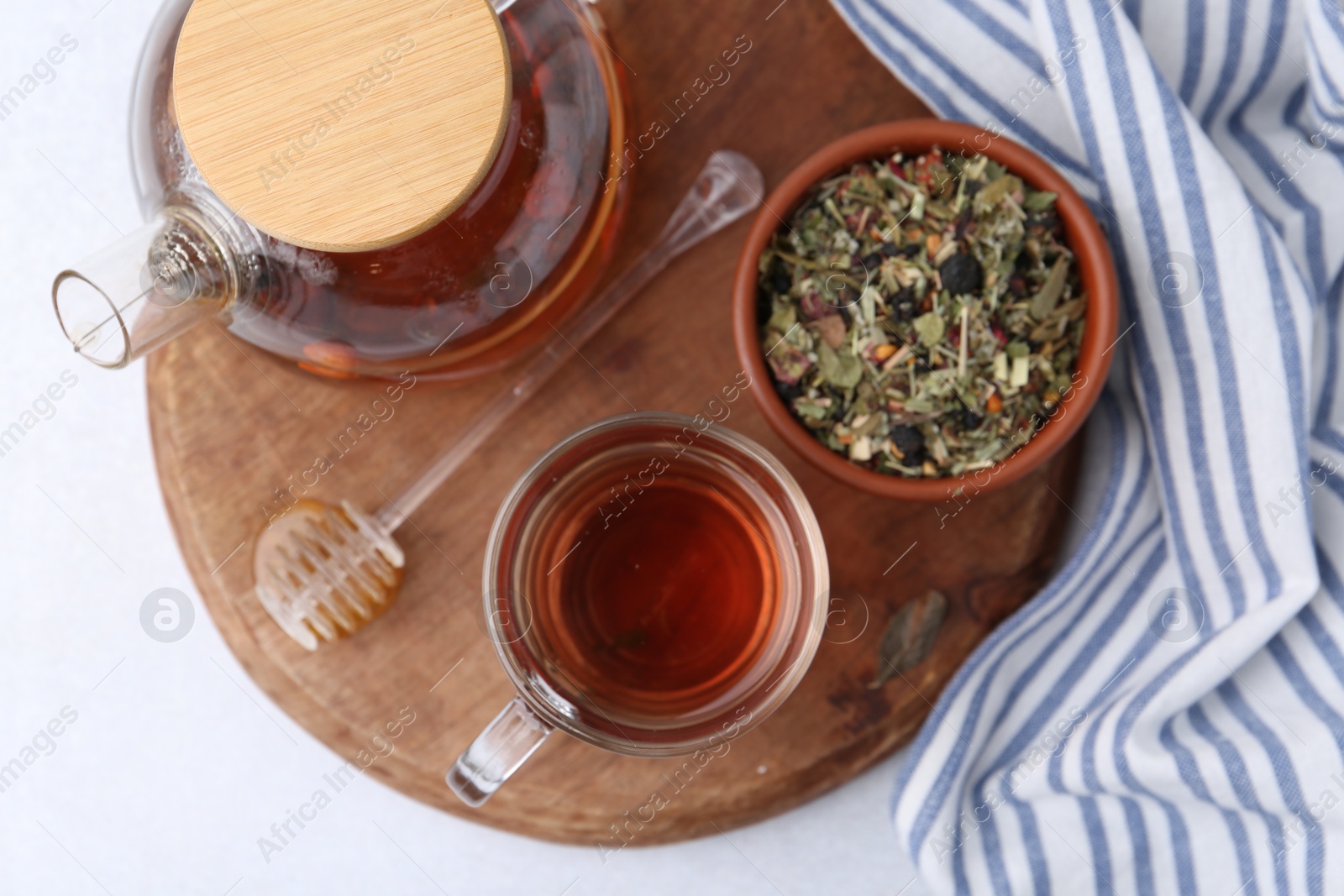 Photo of Delicious herbal tea, honey and dry leaves on white table, top view