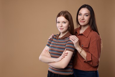 Photo of Portrait of beautiful mother with teenage daughter on dark beige background, space for text