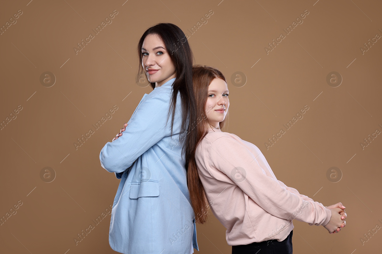 Photo of Portrait of beautiful mother with teenage daughter on dark beige background