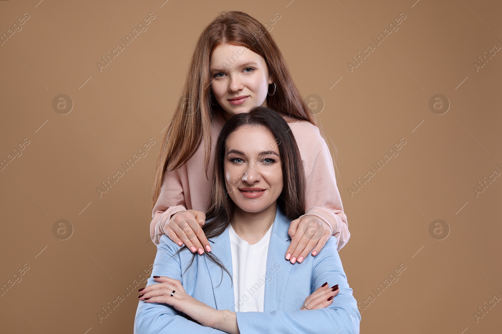 Photo of Portrait of beautiful mother with teenage daughter on dark beige background