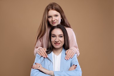 Photo of Portrait of beautiful mother with teenage daughter on dark beige background