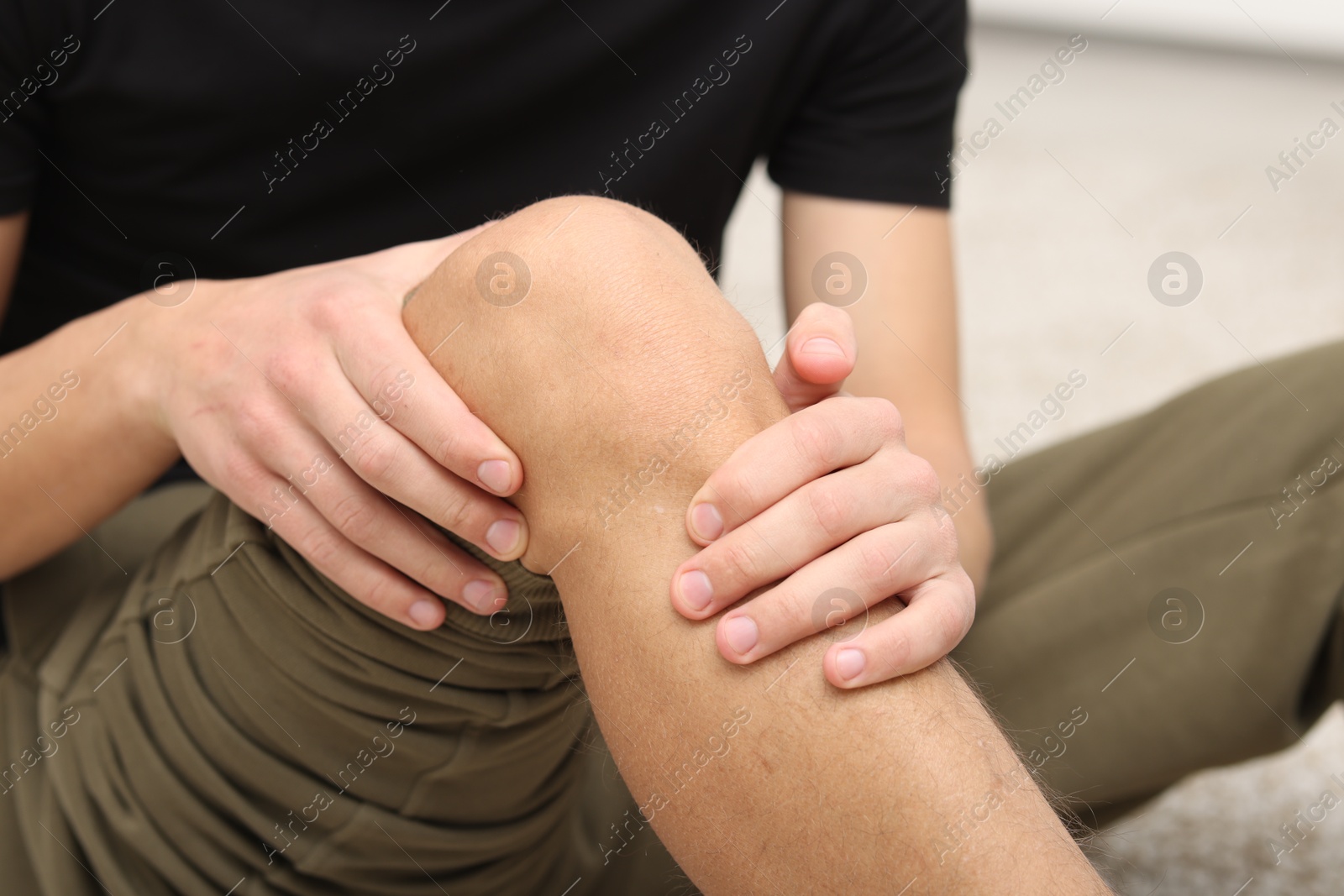 Photo of Young man suffering from pain in knee at home, closeup