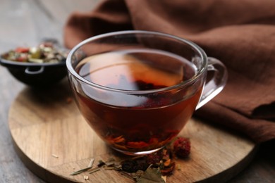 Photo of Delicious herbal tea and dry leaves on wooden table, closeup