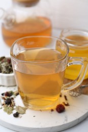 Photo of Delicious herbal tea with honey and dry leaves on white table, closeup