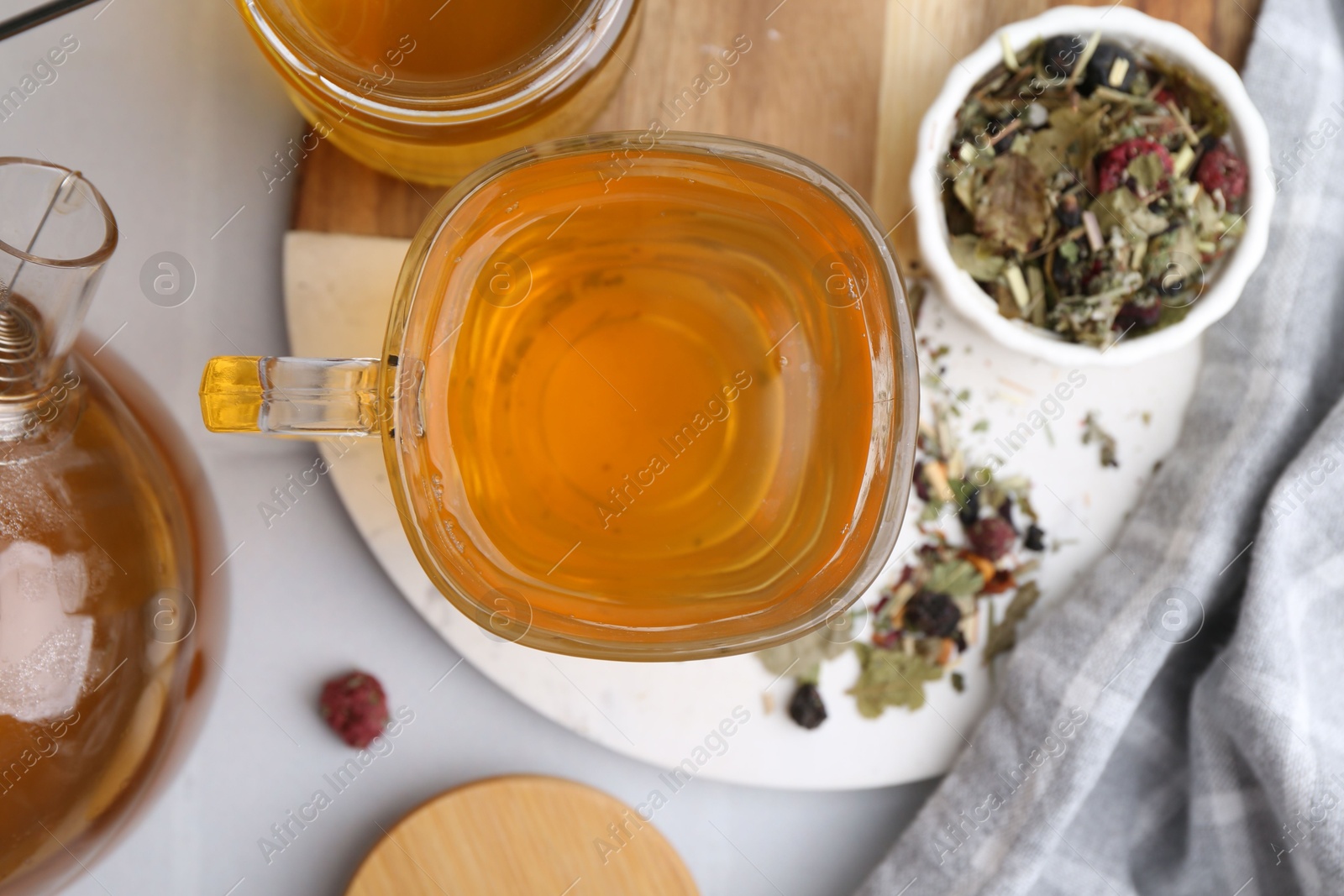 Photo of Delicious herbal tea with honey and dry leaves on white table, flat lay