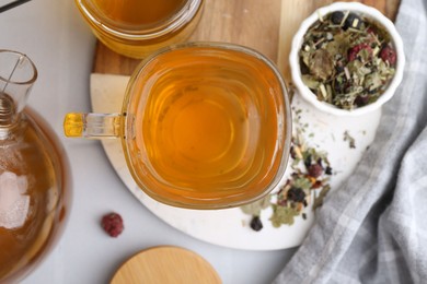 Photo of Delicious herbal tea with honey and dry leaves on white table, flat lay