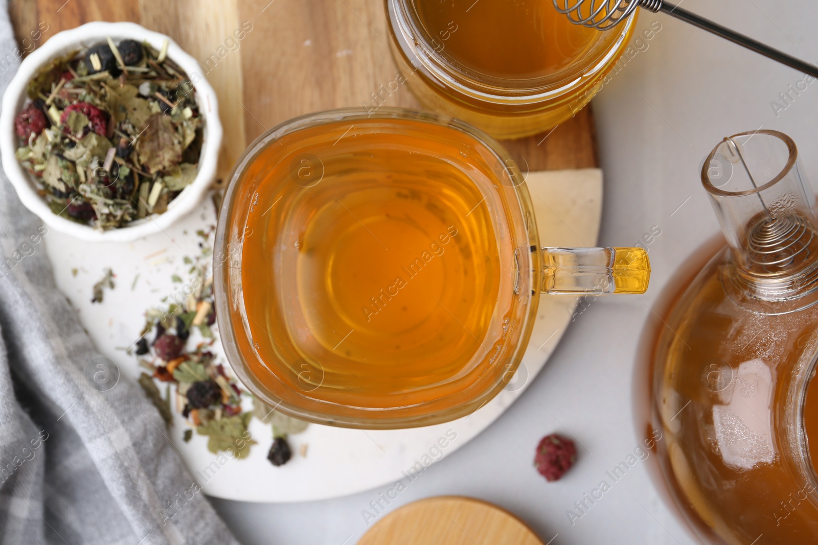 Photo of Delicious herbal tea with honey and dry leaves on white table, flat lay