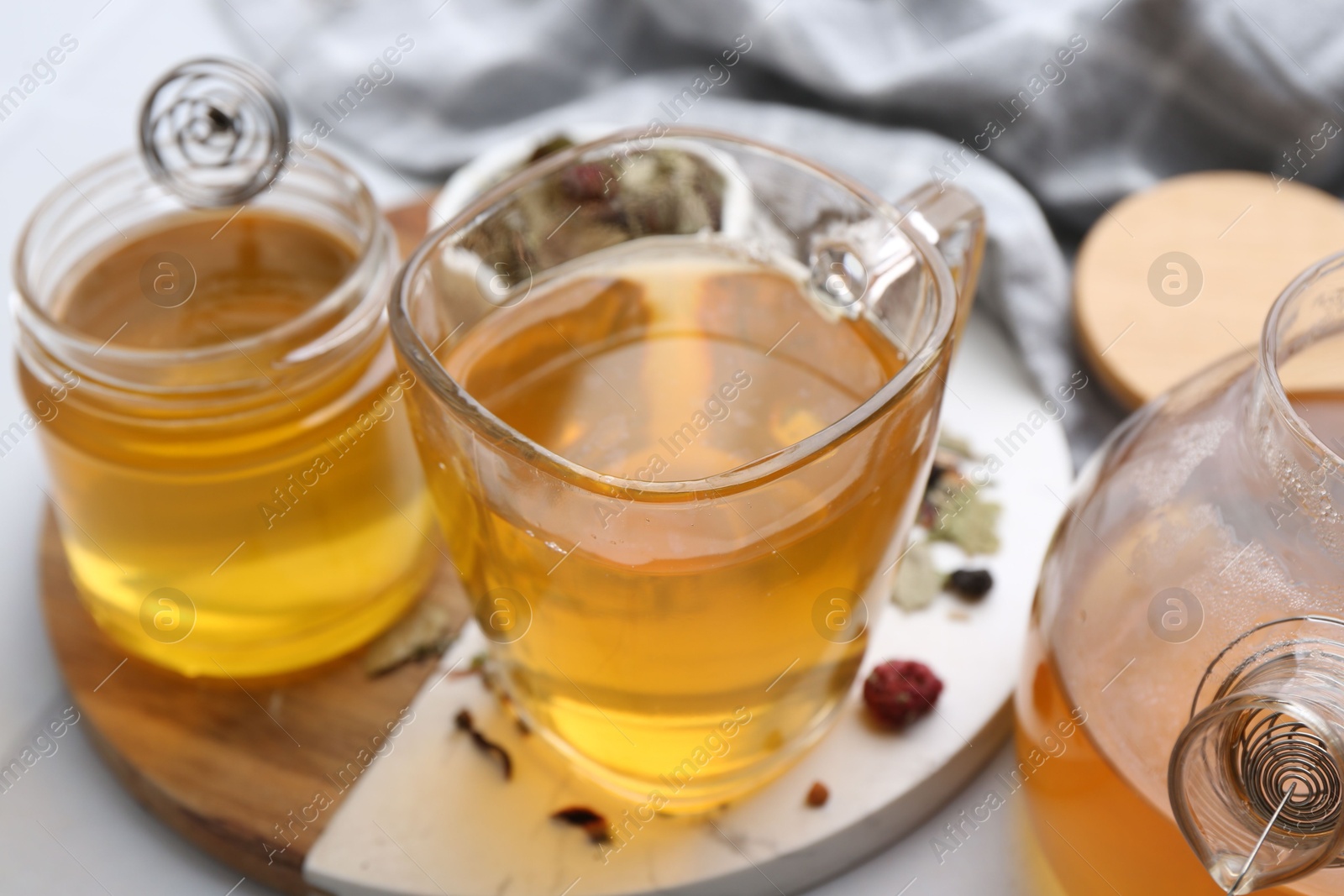 Photo of Delicious herbal tea with honey and dry leaves on white table, closeup