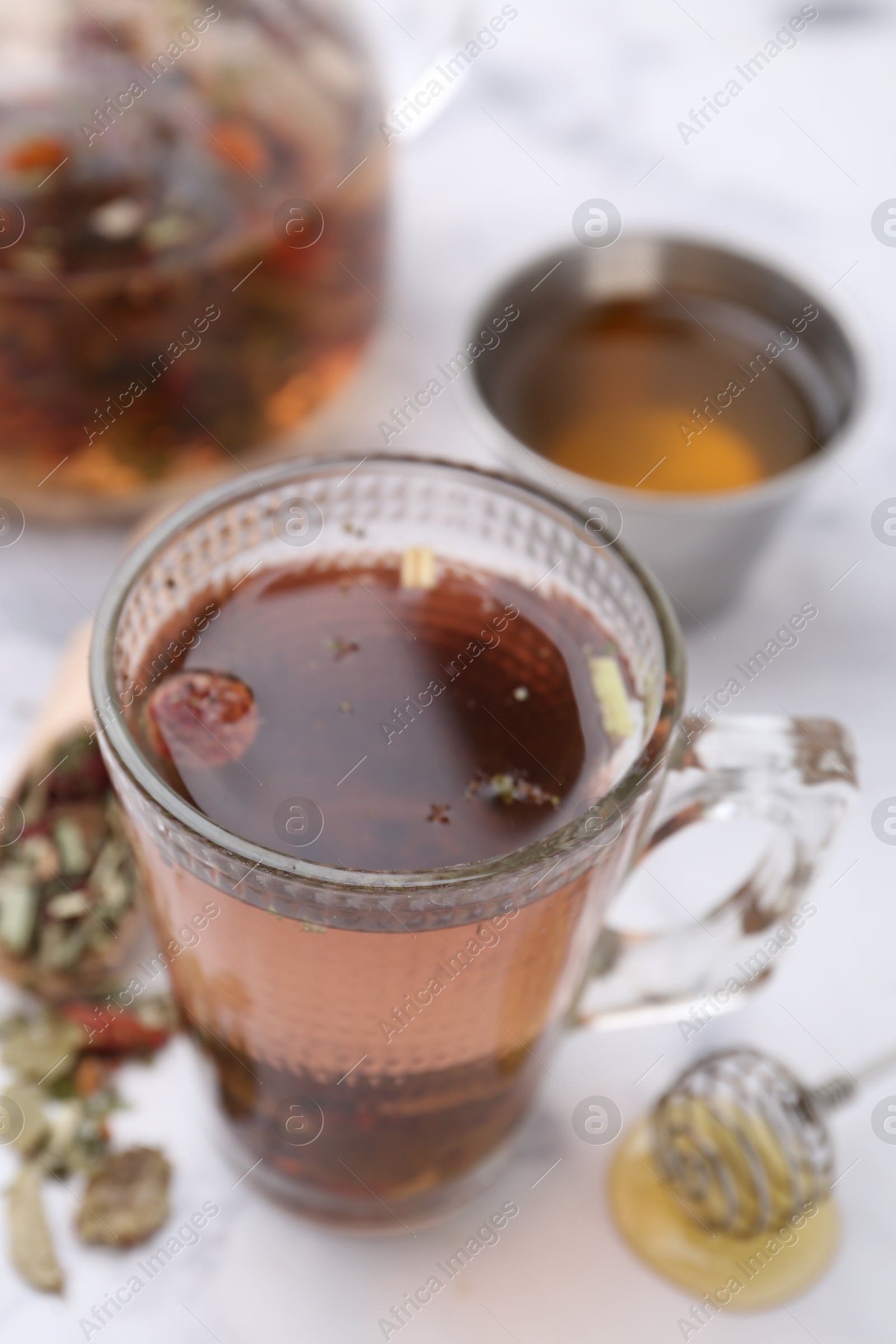 Photo of Delicious herbal tea with honey and dry leaves on white marble table, closeup