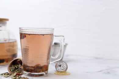 Photo of Delicious herbal tea with honey and dry leaves on white marble table. Space for text