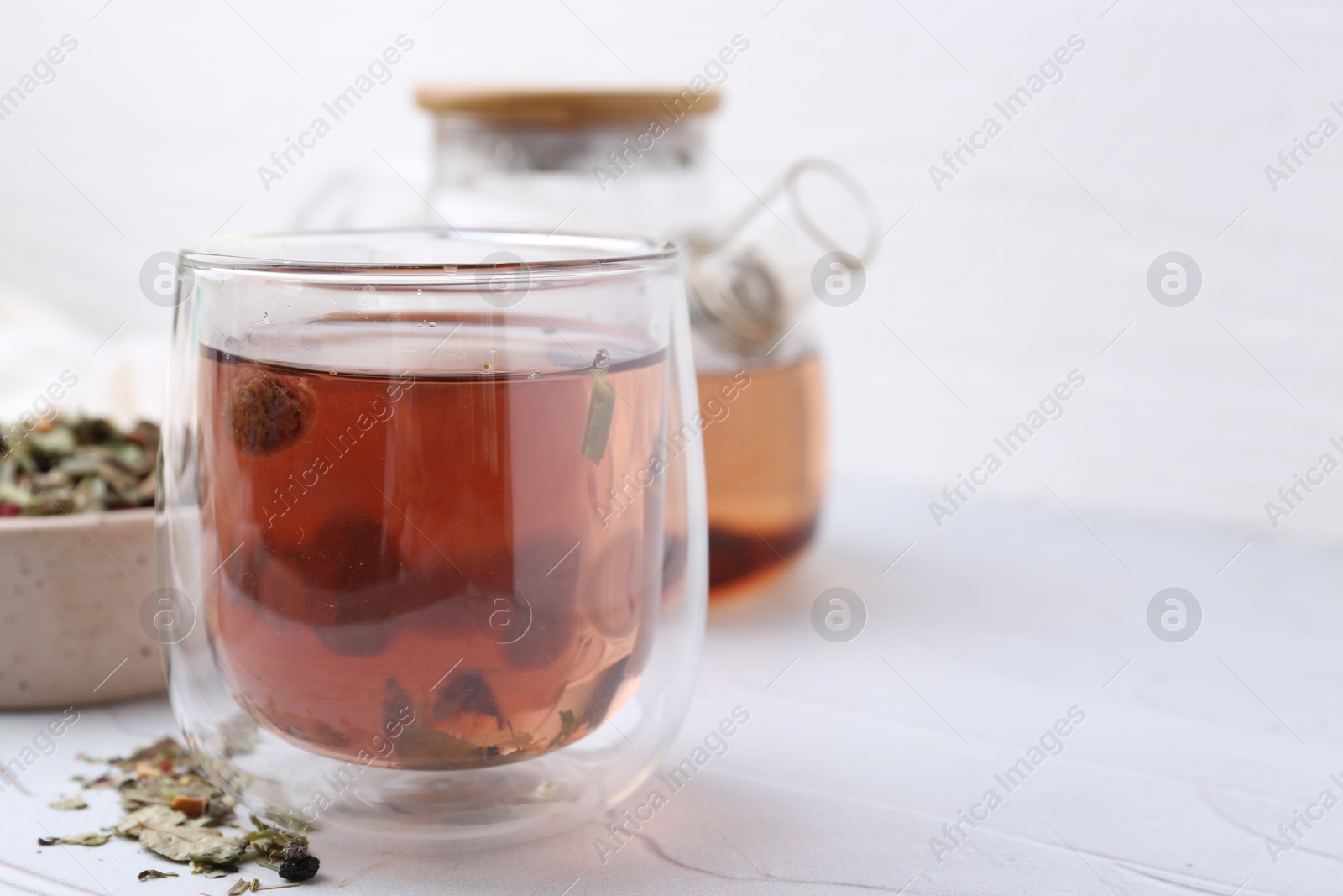 Photo of Delicious herbal tea and dry leaves on white table, closeup. Space for text