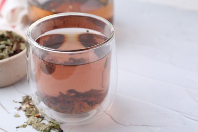 Photo of Delicious herbal tea and dry leaves on white table, closeup. Space for text