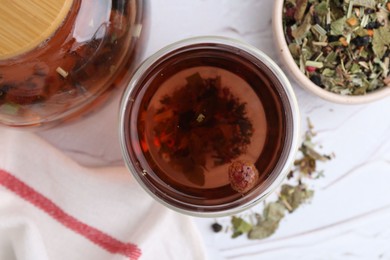 Photo of Delicious herbal tea and dry leaves on white table, flat lay