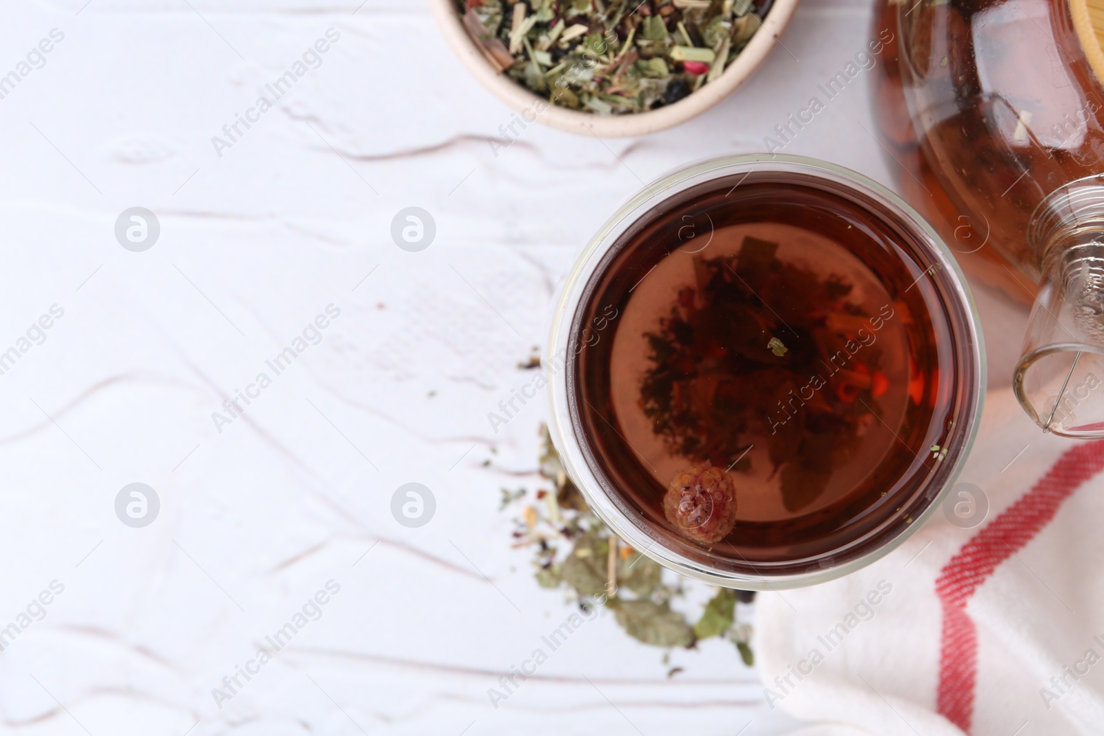 Photo of Delicious herbal tea and dry leaves on white table, flat lay. Space for text