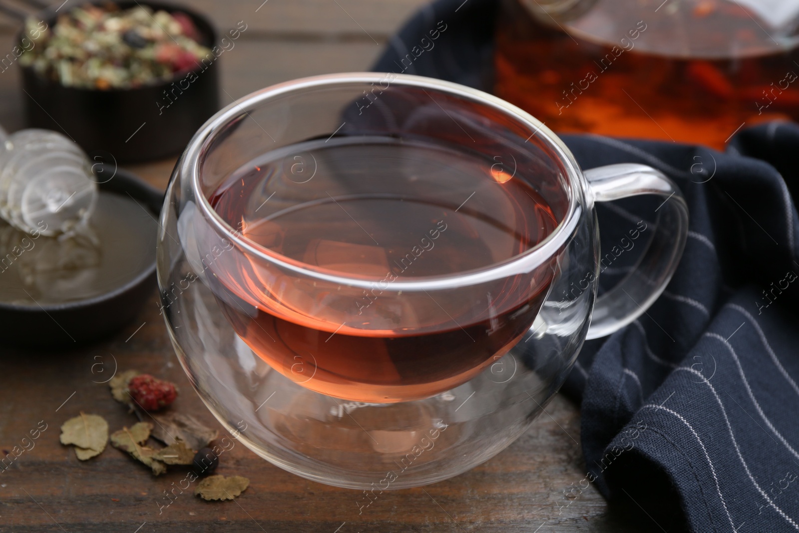 Photo of Delicious herbal tea with honey and dry leaves on wooden table, closeup