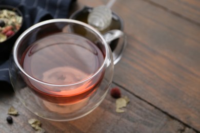 Photo of Delicious herbal tea and dry leaves on wooden table, closeup. Space for text