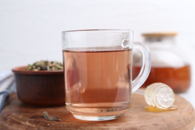 Photo of Delicious herbal tea, honey and dry leaves on white table, closeup