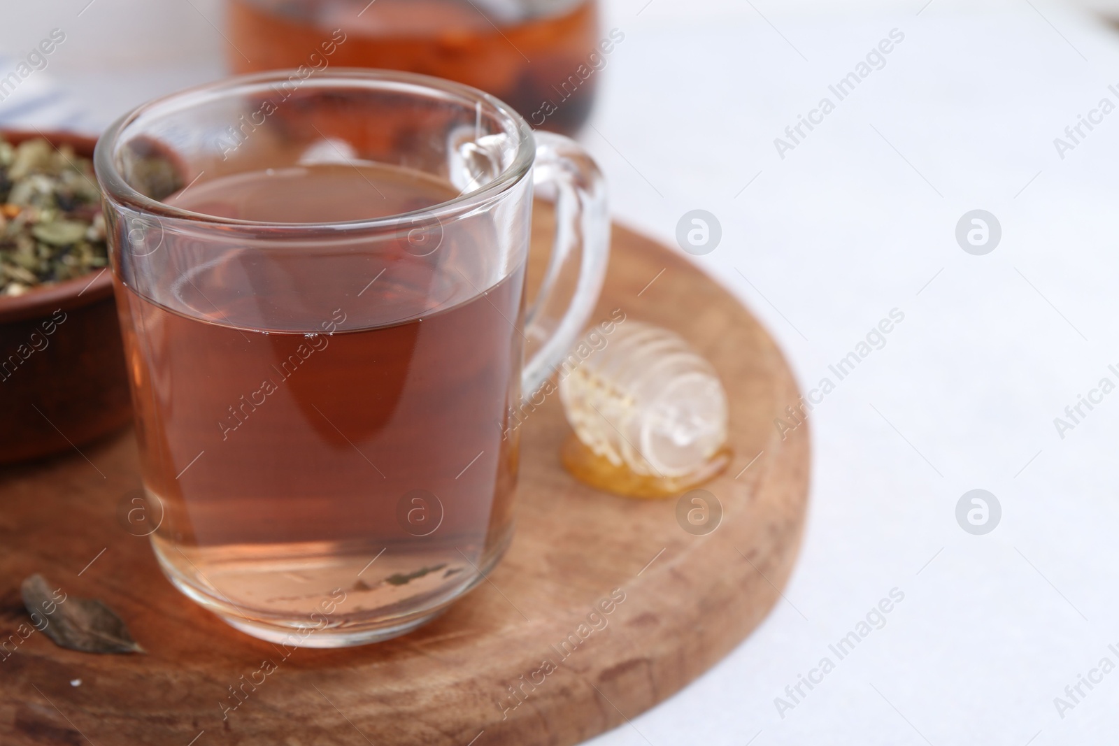 Photo of Delicious herbal tea, honey and dry leaves on white table, closeup. Space for text