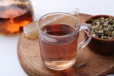 Photo of Delicious herbal tea, honey and dry leaves on white table, closeup