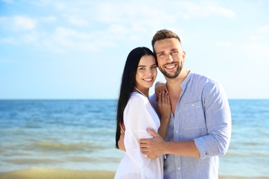 Photo of Happy young couple near sea on sunny day. Beach holiday