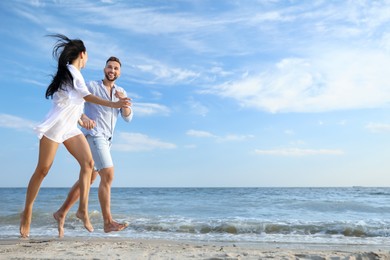 Photo of Happy young couple running together on beach