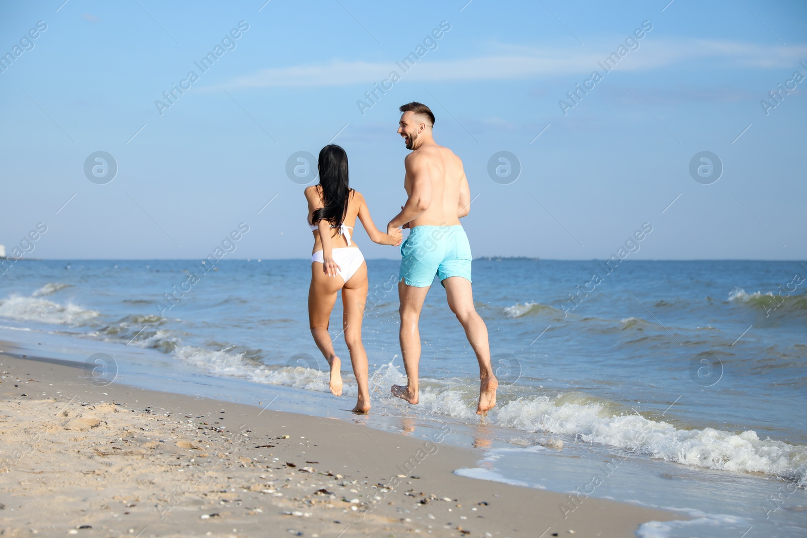 Photo of Happy young couple running together on beach