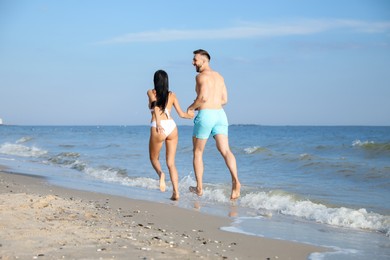 Happy young couple running together on beach