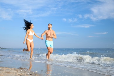 Photo of Happy young couple running together on beach