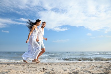 Photo of Happy young couple running together on beach