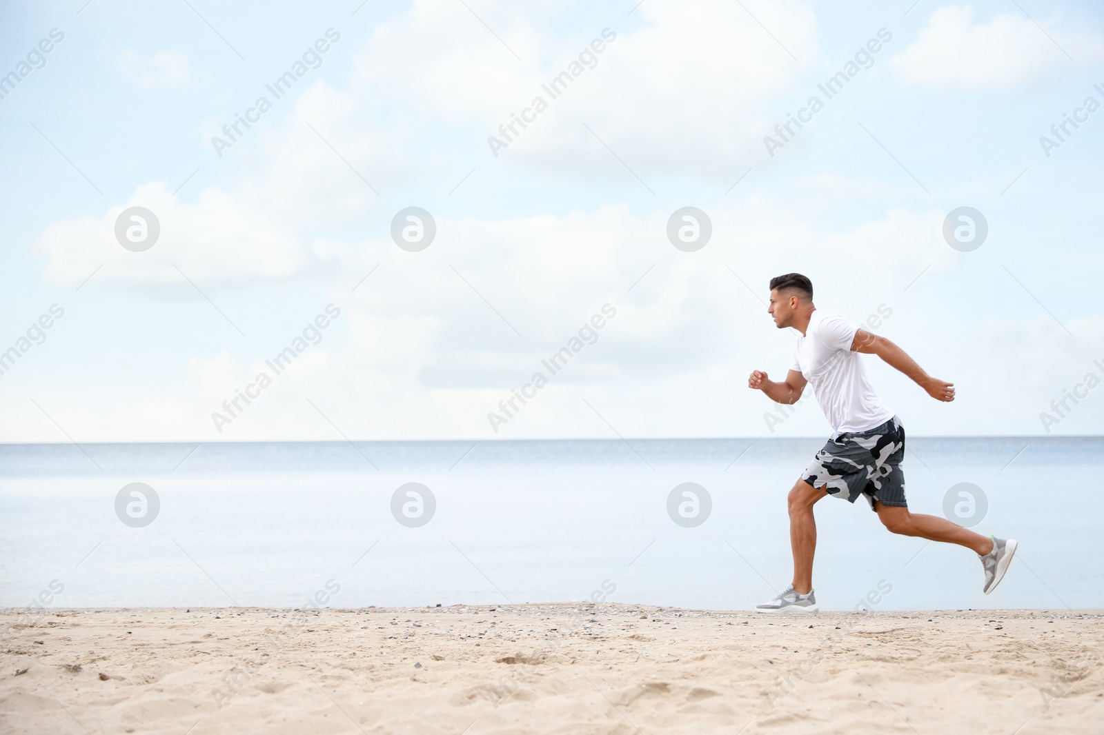 Photo of Muscular man running on beach, space for text. Body training