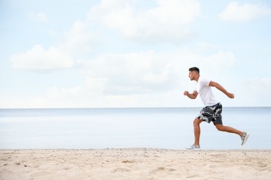 Photo of Muscular man running on beach, space for text. Body training