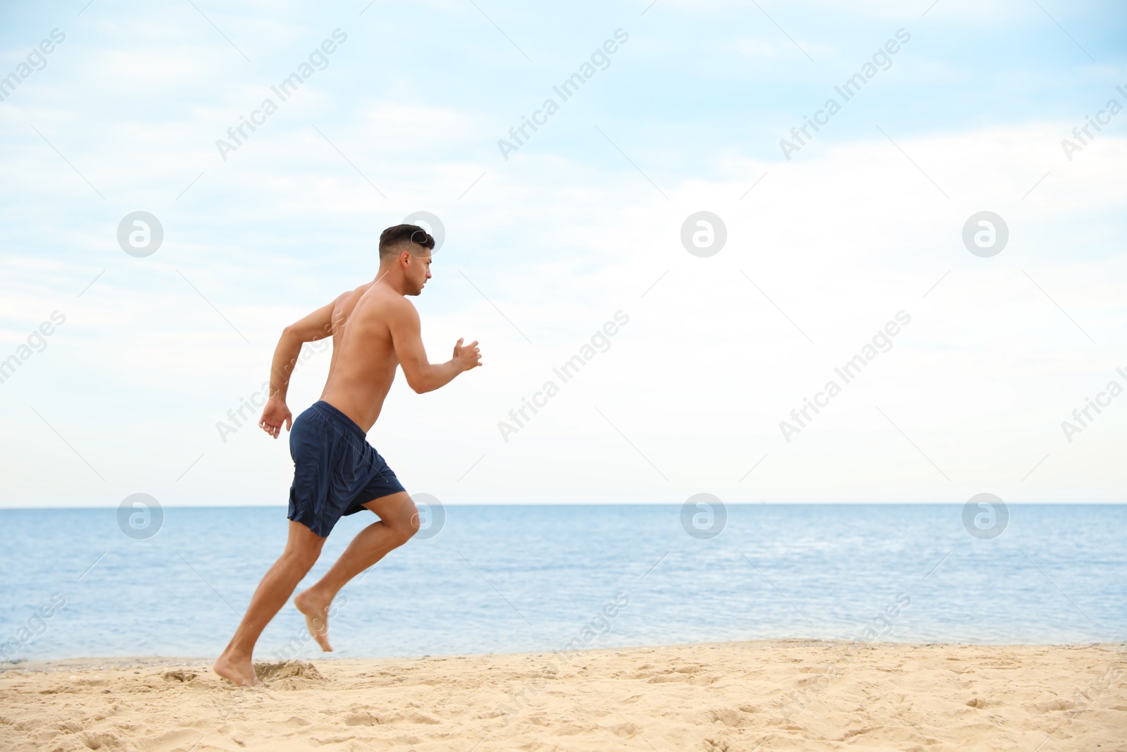 Photo of Muscular man running on beach, space for text