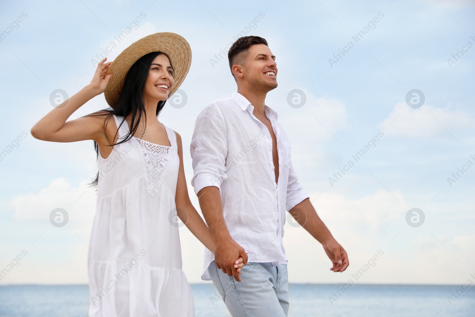 Photo of Lovely couple holding hands while walking near sea