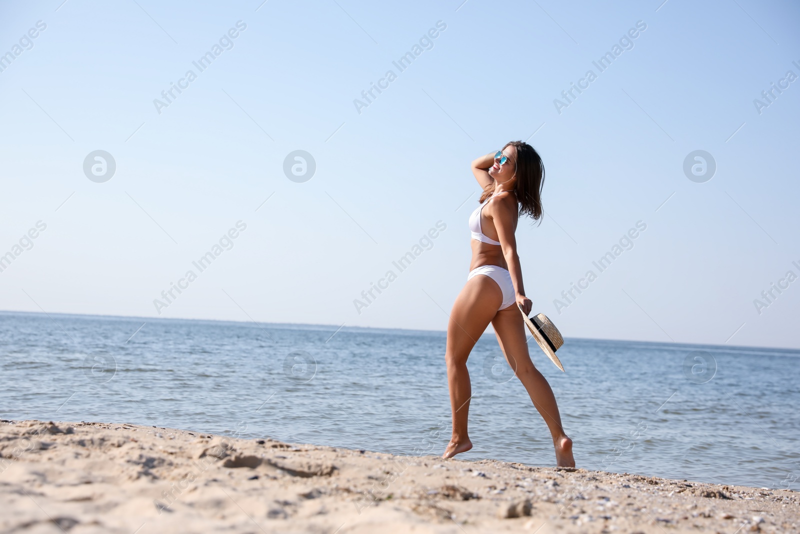 Photo of Young woman with beautiful body on sandy beach. Space for text