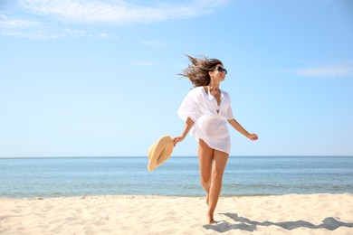 Photo of Young woman with beautiful body on sandy beach. Space for text