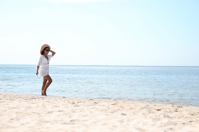 Photo of Young woman with beautiful body on sandy beach. Space for text