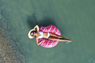 Young woman with beautiful body on inflatable ring in sea, top view