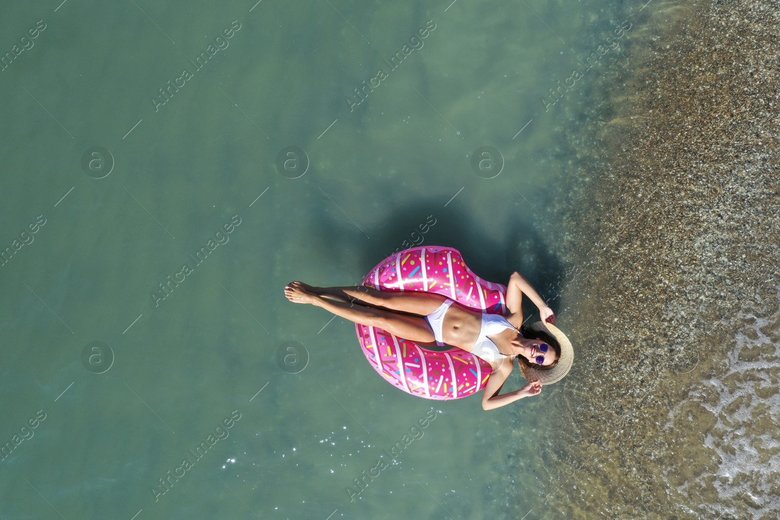 Photo of Young woman with beautiful body on inflatable ring in sea, top view