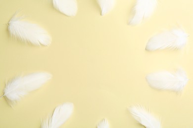 Photo of Frame of beautiful fluffy feathers on beige background, flat lay. Space for text