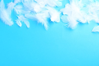 Photo of Beautiful fluffy feathers on light blue background, flat lay. Space for text