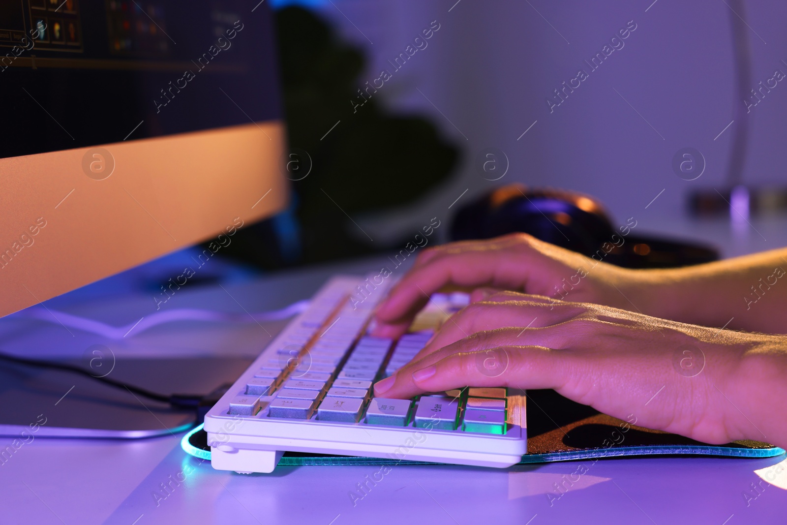 Photo of Woman using computer keyboard at white table indoors, closeup