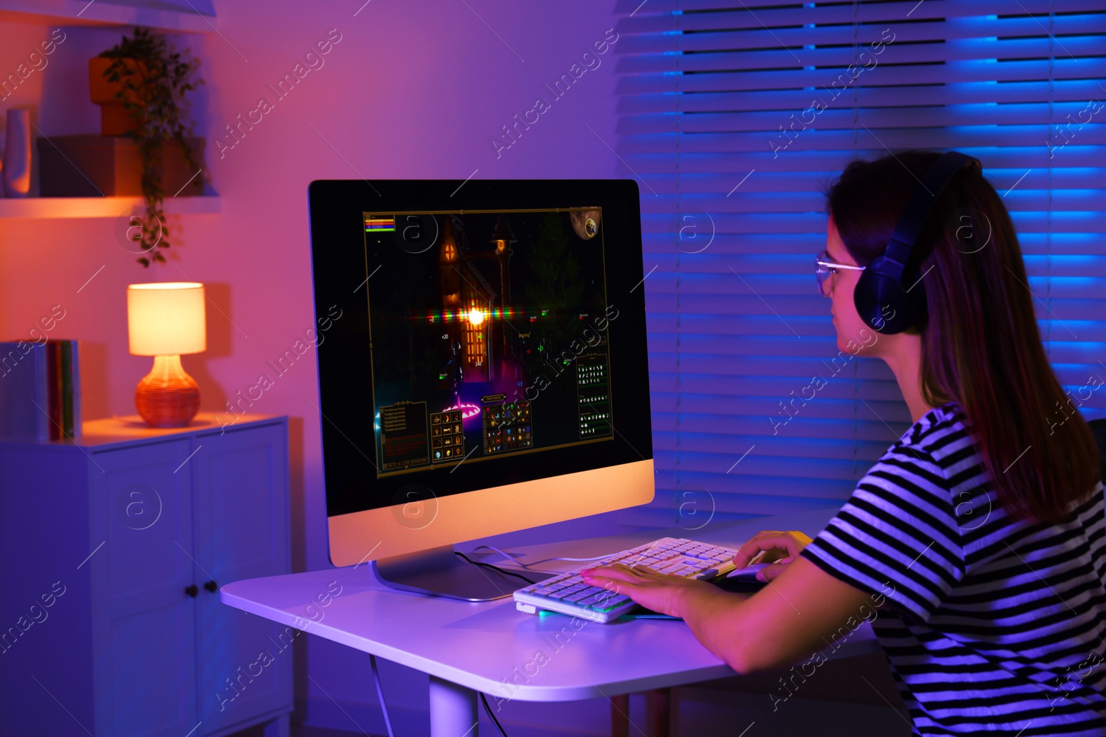 Photo of Woman playing video game with keyboard at table indoors