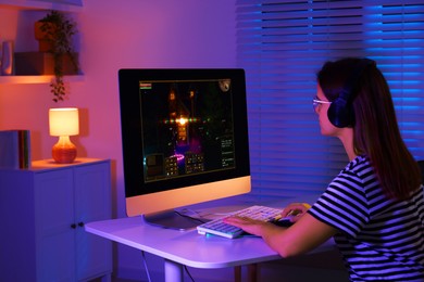 Photo of Woman playing video game with keyboard at table indoors